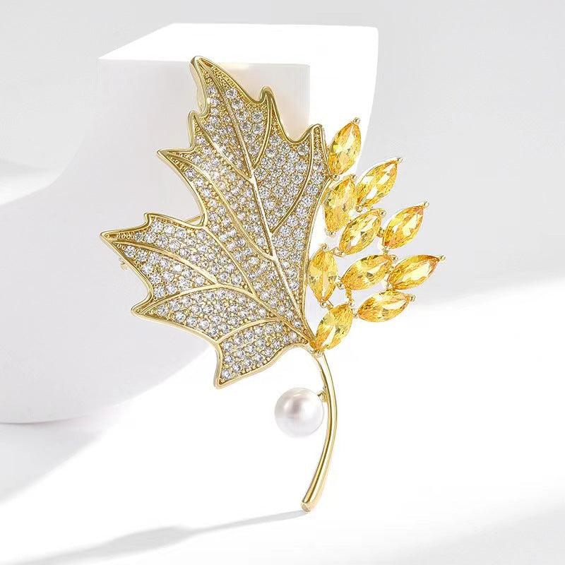 Golden maple leaf brooch with pearl accent