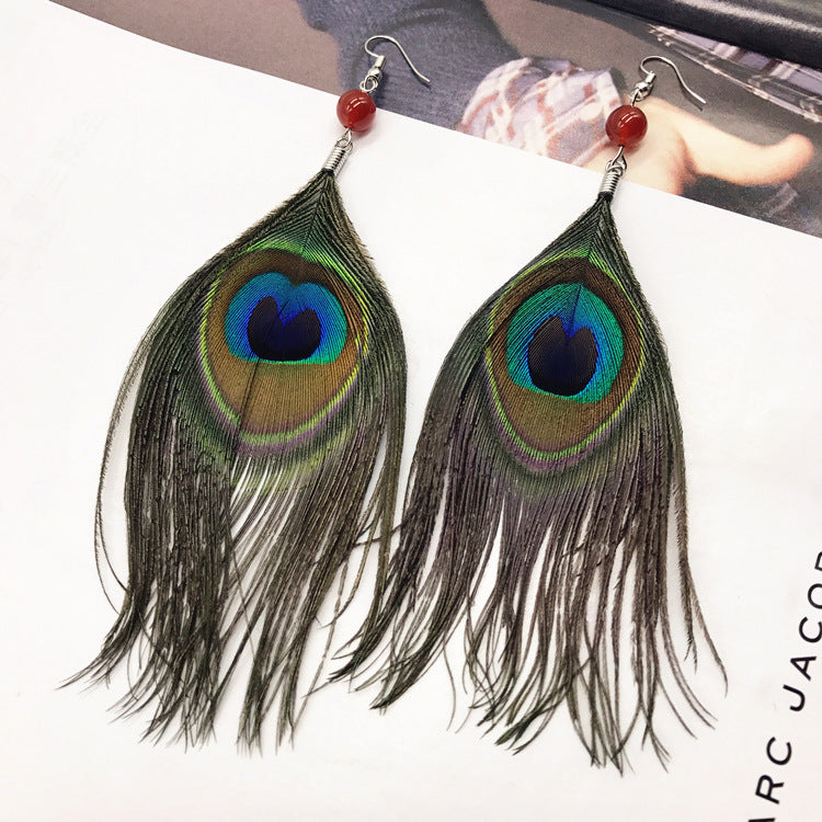 Close-up of stylish tassel earrings showcasing peacock feathers