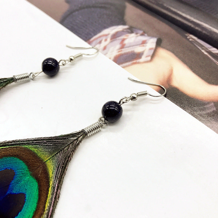 Close-up of stylish tassel earrings showcasing peacock feathers